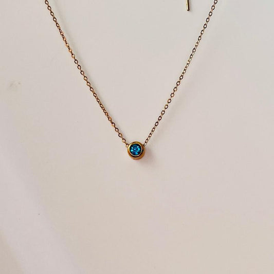 a gold chain necklace with a aqua marine stone pendant