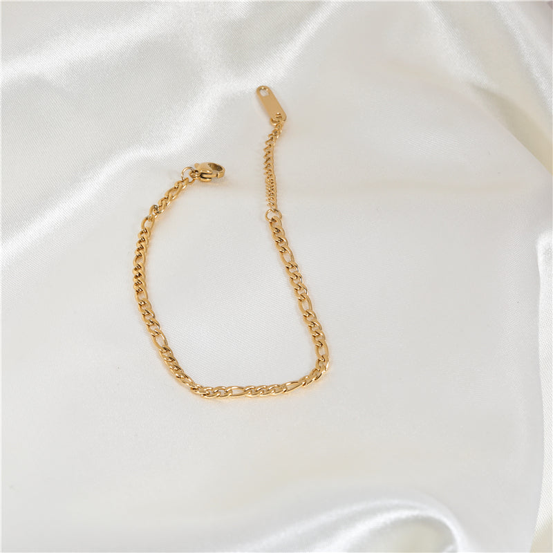 figaro chain bracelet in gold on a satin sheet