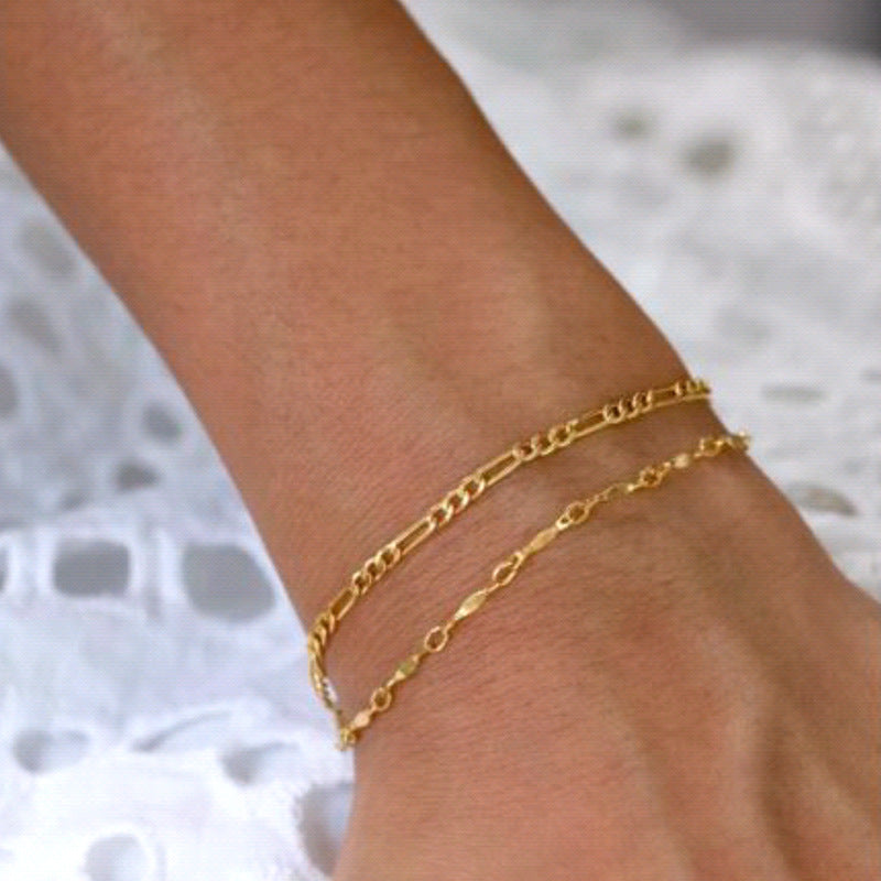 gold figaro chain bracelet on a wrist