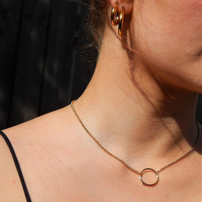 woman wearing a gold necklace with an open circle pendant