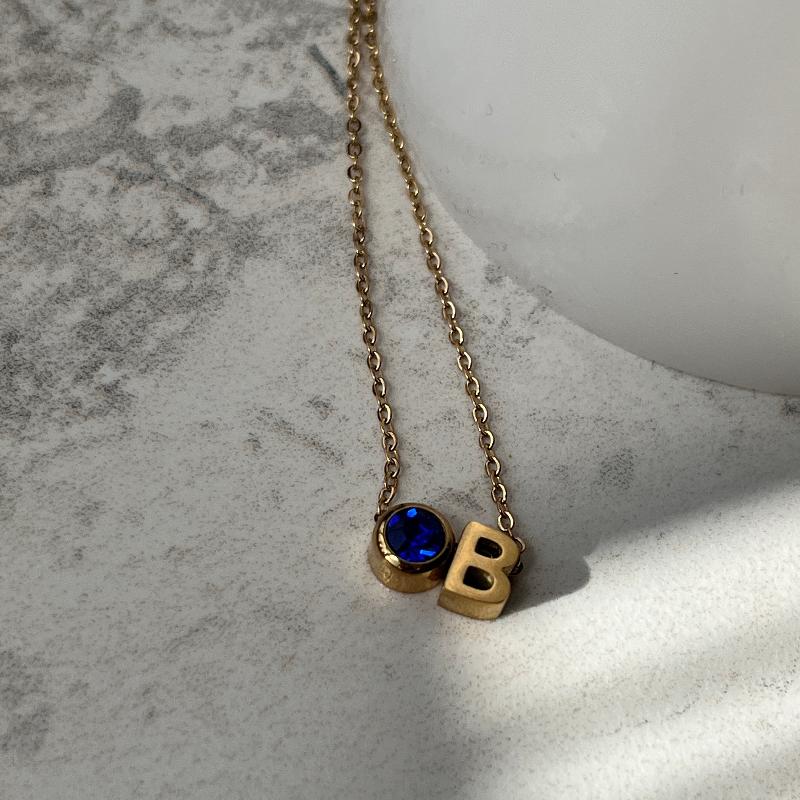 gold necklace with initial b and a blue birthstone