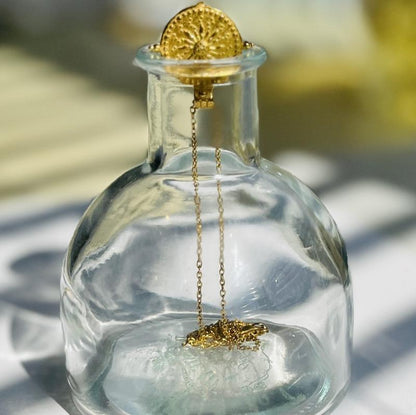 sun pendant necklace on top of a glass bottle